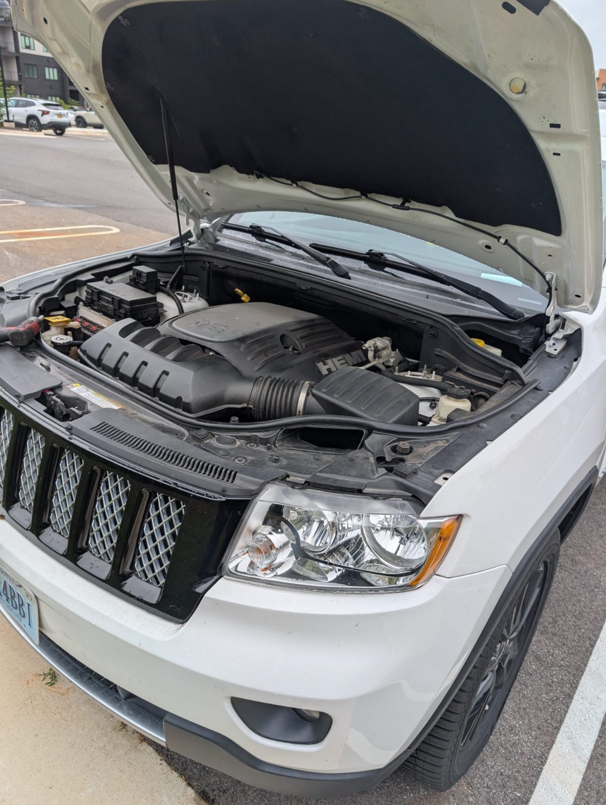 White SUV parked with the hood up, showing the engine and air intake during a diagnostic check